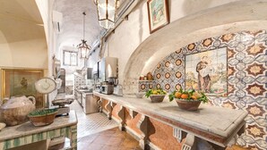 A kitchen with a marble countertop, a sink, and a tiled backsplash with religious artwork. - AMORE RENTALS - Villa San Giacomo – Historic Luxury Villa with Sea View (Positano)