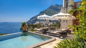 A poolside area with lounge chairs and umbrellas, overlooking a mountainous coastline. - AMORE RENTALS - Villa San Giacomo – Historic Luxury Villa with Sea View (Positano)