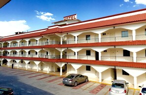 A multi-story hotel with a red-tiled roof, balconies, and a sign indicating it is a hotel.