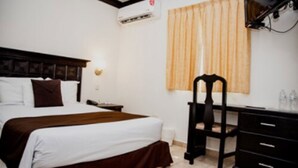 A hotel room with a bed, a desk, a chair, a television, and an air conditioning unit. - Hotel Go Inn (Monclova)