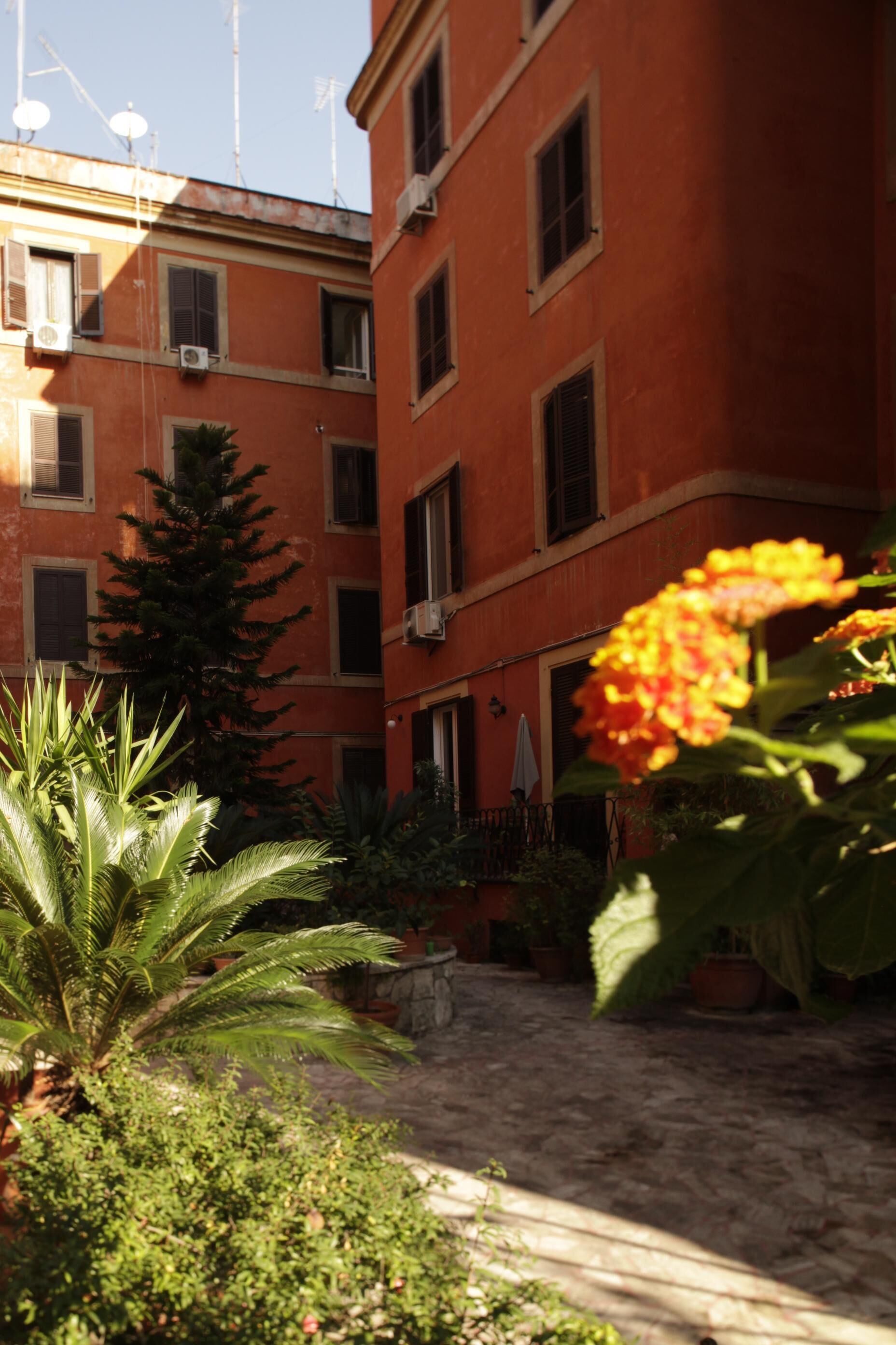 Une cour intérieure agrémentée de plantes en pot et un bâtiment doté de nombreuses fenêtres.