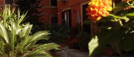 Une cour intérieure agrémentée de plantes en pot et un bâtiment doté de nombreuses fenêtres.
