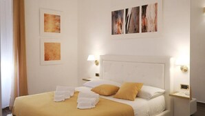 A hotel room with a large bed, white headboard, and two bedside tables with lamps. There are three framed artworks on the wall. - Enchanting apartment 2 minutes away from the Vatican Museums (Roma)