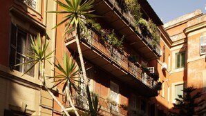 A courtyard with potted plants, a staircase, and a building with balconies. - Enchanting apartment 2 minutes away from the Vatican Museums (Roma)