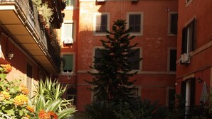 A courtyard with potted plants and a tree, surrounded by buildings with balconies and windows. - Enchanting apartment 2 minutes away from the Vatican Museums (Roma)