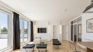 A spacious living area with large windows, a flat-screen TV, and modern furniture. - Apartment Villa Mila (Kaštel Novi)