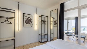 A modern hotel room with a large bed, a wardrobe with a hanging rack, a mirror, and artwork on the walls. - Apartment Villa Mila (Kaštel Novi)