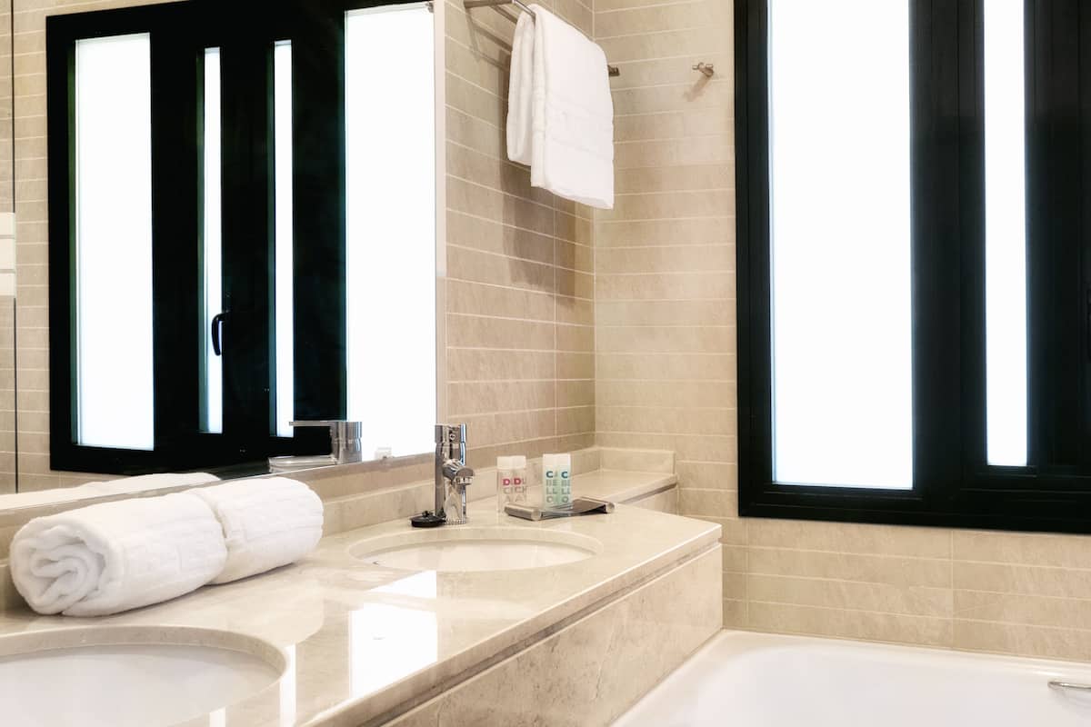A bathroom with a sink, mirror, and bathtub.
