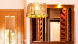 Ein Holztisch mit vier Stühlen, eine Hängelampe und ein Fenster mit Holzjalousien.