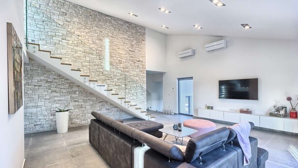 A spacious living area with a stone wall, a staircase, a large sofa, a flat-screen TV, and a dining area. - Villa Fortuna - in historic town Buje with 4 bedrooms and a pool, near the beach by MyWaycation (Kaštel)