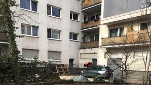 A parking area with a paved surface, a car, and a building with multiple windows and balconies. - Hotel Isabella (Frankfurt)