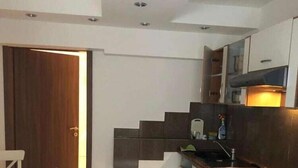 A compact kitchen with a dining area, featuring a wooden door, a tiled floor, and modern cabinetry. - Hotel Isabella (Frankfurt)