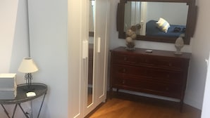 A bedroom with a bed, a dresser, a mirror, and a lamp.