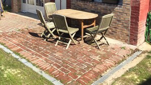 A patio with a brick floor, a wooden table, and four chairs.