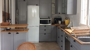 A compact kitchen with grey cabinets, a white refrigerator, a microwave, and a sink.