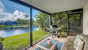 A spacious room with large windows overlooking a pool and lush greenery.