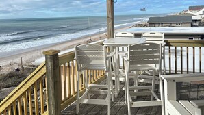 A wooden deck with white chairs and tables overlooking a beach. - FALL SPECIAL PRICING Beautifully Remodeled Surf City Oceanfront on the beach (Surf City)