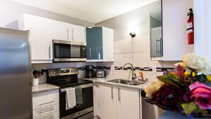 Una cocina moderna con electrodomésticos de acero inoxidable, armarios blancos y encimera de granito.