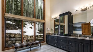 Eine moderne Küche mit dunklen Schränken, einem großen Fenster inklusive Sitzbank und einer Steinwand.