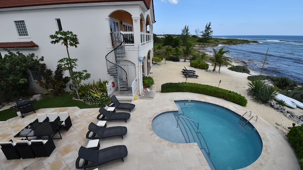 Un espace piscine avec des chaises longues et un escalier menant à un balcon.