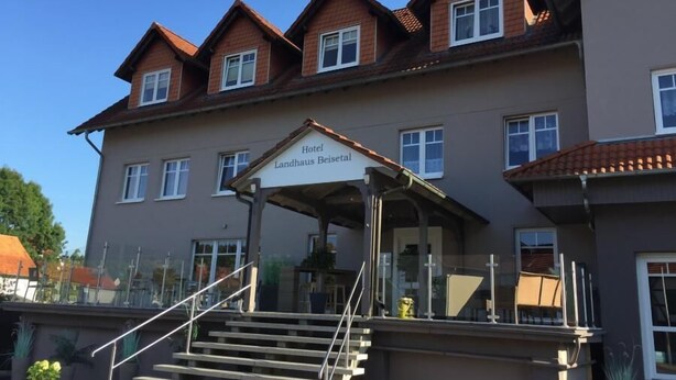 A hotel with a covered entrance, multiple windows, and a staircase leading to the entrance. - Landhaus Beisetal (Knullwald)