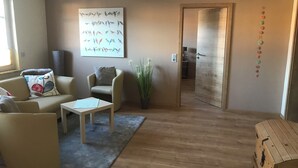 Ein Wohnzimmer mit Sofa, Sessel, Couchtisch und einem Bild an der Wand.