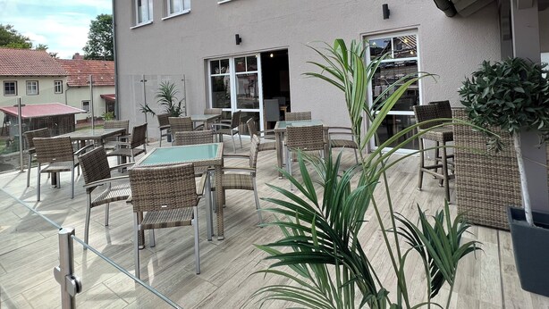 A building with multiple windows, outdoor seating, and potted plants. - Landhaus Beisetal (Knullwald)