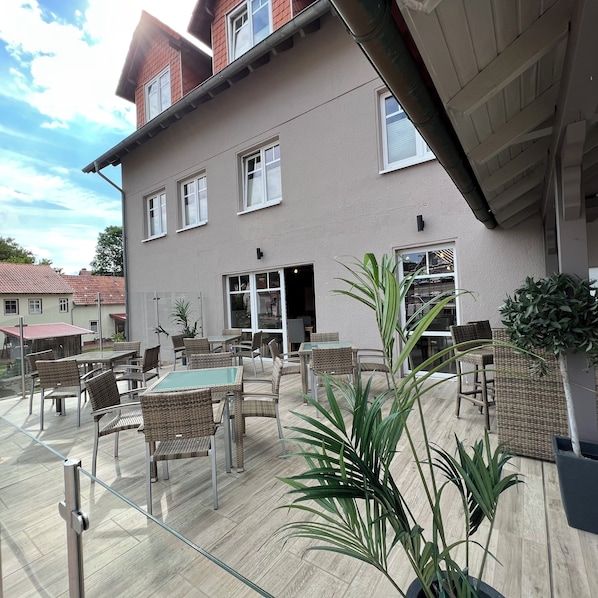 A building with multiple windows, outdoor seating, and potted plants. - Landhaus Beisetal (Knullwald)