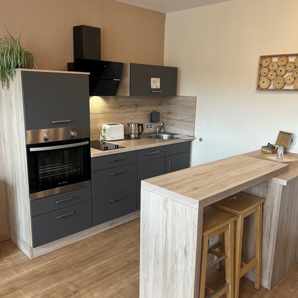 A modern kitchen with a built-in oven, a toaster, a coffee maker, and a sink. - Landhaus Beisetal (Knullwald)