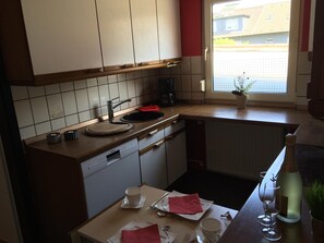 A kitchen with a dishwasher, a coffee maker, and a window with a view of buildings.