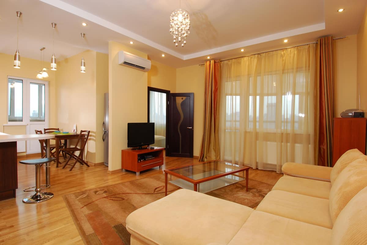 A living room with a sofa, a glass coffee table, a TV, and a dining area with chairs and a table.