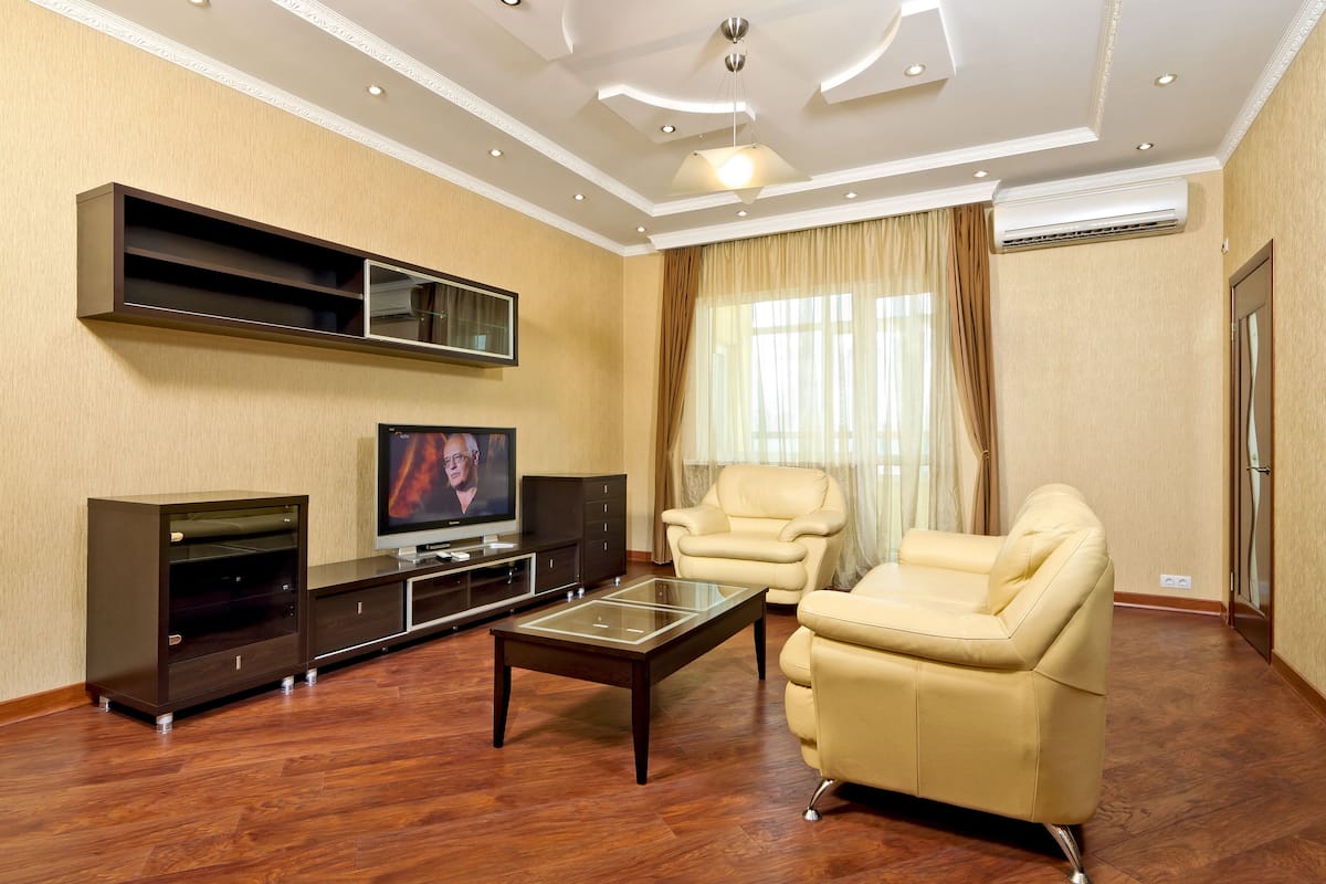 A living room with a flat-screen TV, leather sofas, a glass coffee table, and a built-in entertainment unit.