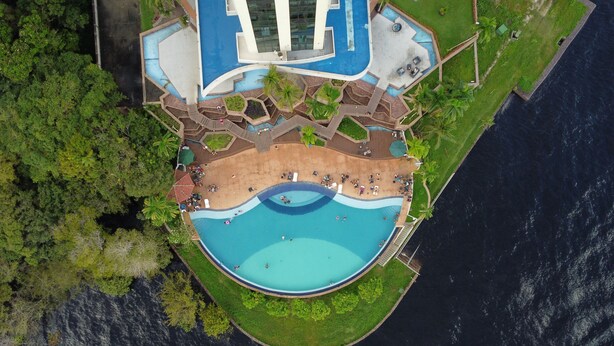 Vista aérea de un resort con una piscina grande, una zona de playa y abundante vegetación.