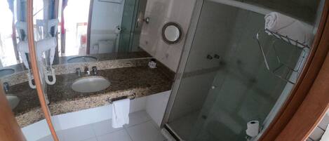 A bathroom with a sink, mirror, towel rack, and a glass-enclosed shower area.
