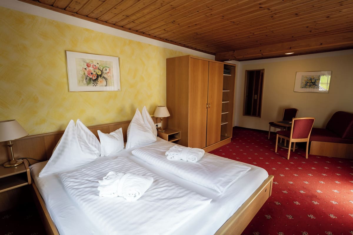 A hotel room with a large bed, a wardrobe, a desk, and a chair.