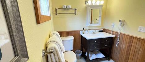 A bathroom with a toilet, sink, mirror, and towel rack.
