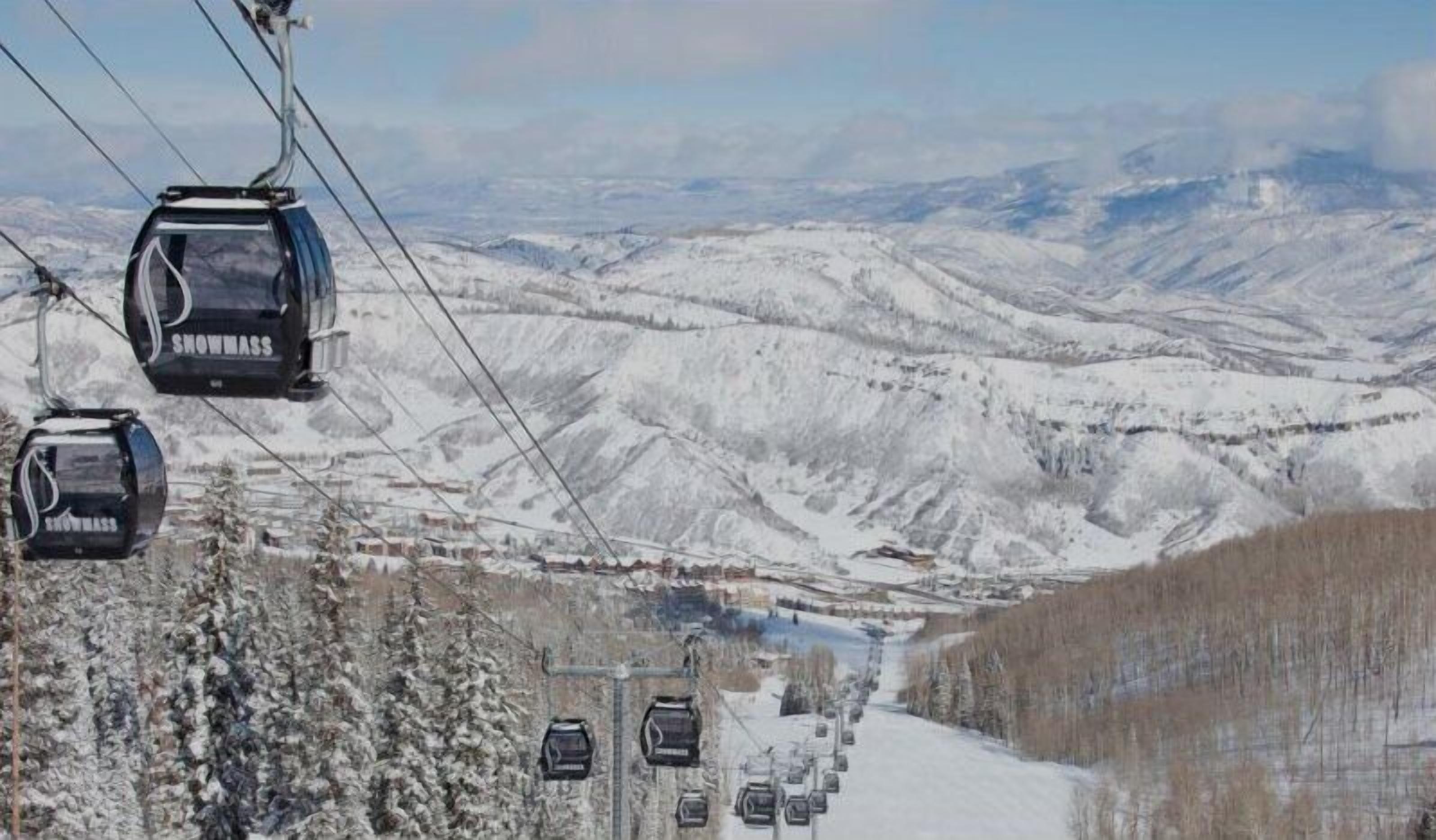 Um teleférico com cabines a percorrer uma paisagem montanhosa coberta de neve.