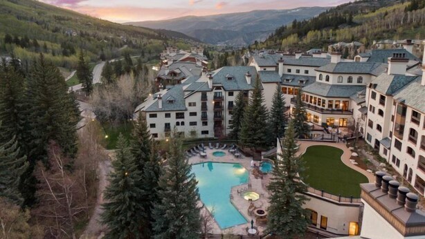 A resort with multiple buildings, a swimming pool, and a mountainous backdrop. - Beaver Creek Charter 2 Bed (Avon)