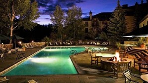 A nighttime swimming pool area with lounge chairs and a fire pit. - Beaver Creek Charter 2 Bed (Avon)
