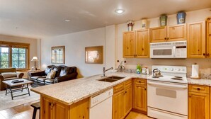 A kitchen with wooden cabinets, a white stove, and a granite countertop. - 1 Bedroom Colorado Vacation Rental in River Run Village Steps from the River Run Gondola (Keystone)