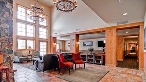 A spacious lobby with a stone accent wall, large windows, a fireplace, and a modern chandelier. - 1 Bedroom Colorado Vacation Rental in River Run Village Steps from the River Run Gondola (Keystone)