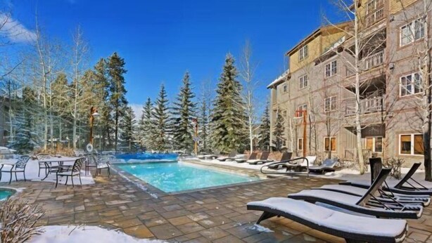 A pool area with lounge chairs and a building in the background. - 1 Bedroom Colorado Vacation Rental in River Run Village Steps from the River Run Gondola (Keystone)