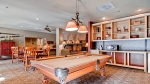 A pool table in a room with a wooden cabinet and shelves.