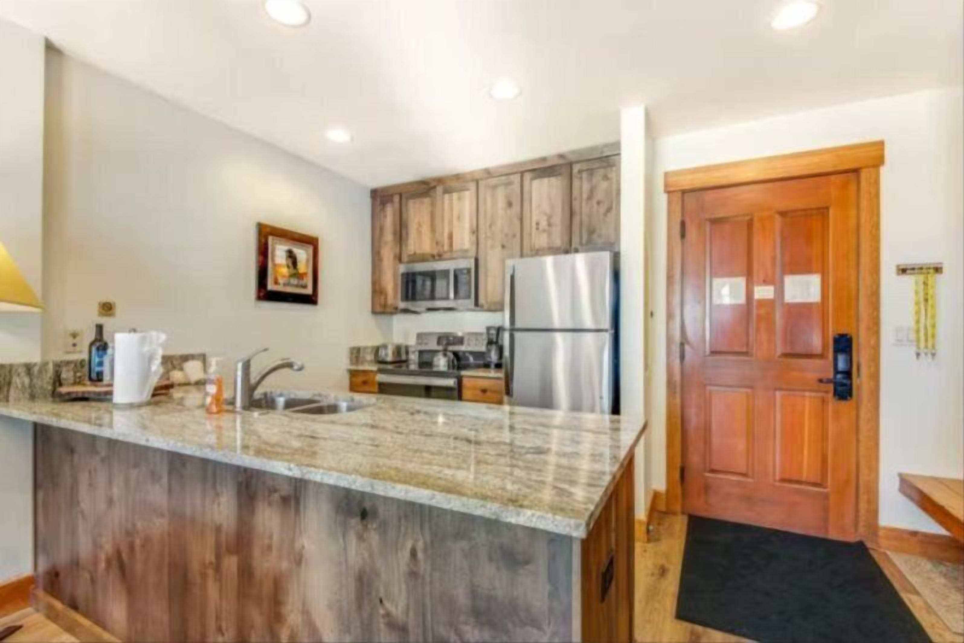 A kitchen with wooden cabinets, stainless steel appliances, and a granite countertop.