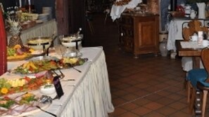 A dining area with a long table set for a meal, featuring various dishes and a buffet setup. - Hotel Schmuckkästchen (Miltenberg)