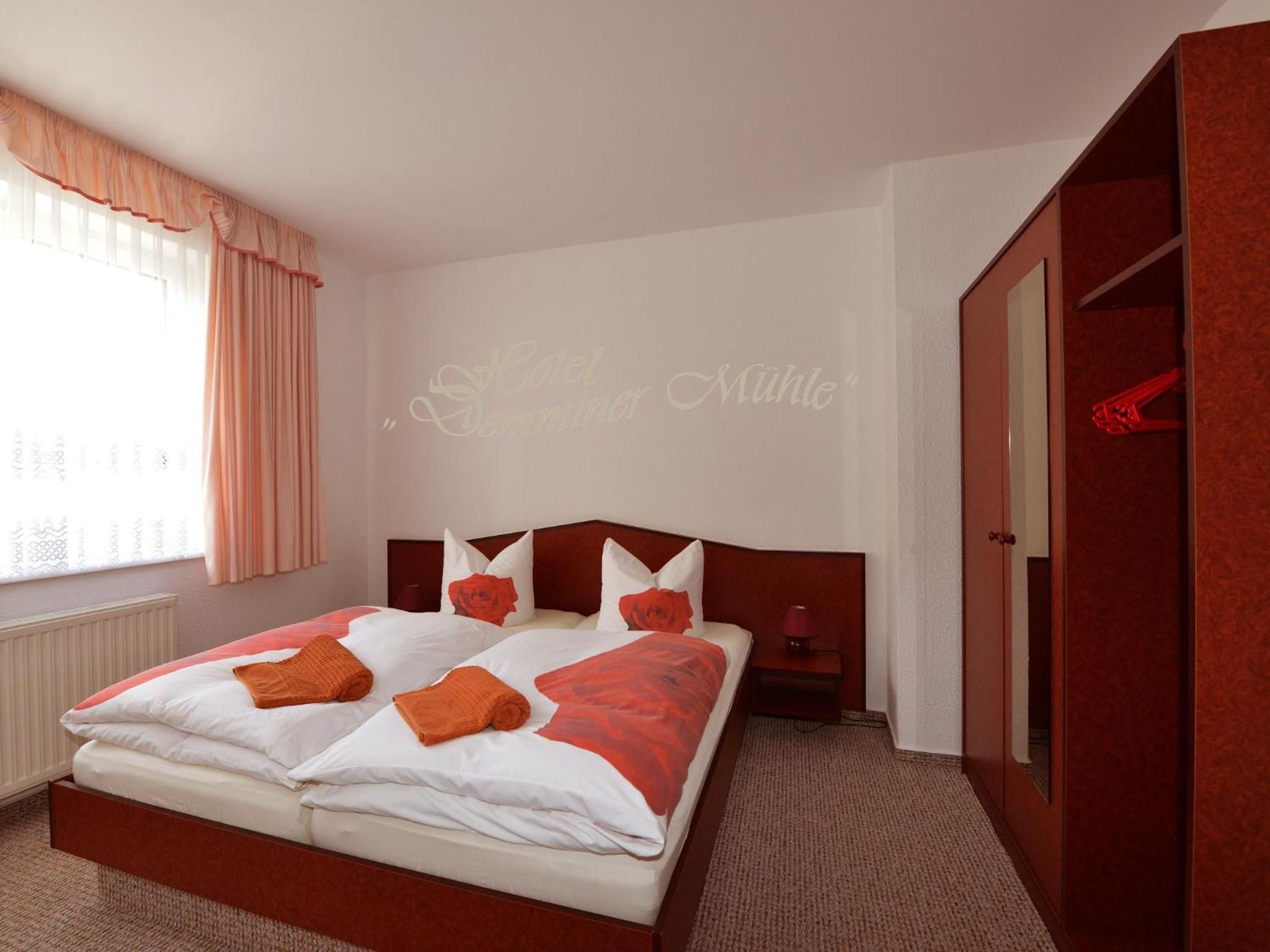 A hotel room with a large bed, a wardrobe, and a window with curtains.