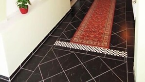 Een gang met tapijten, planten en een zwart-wit vloerkleed.
