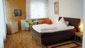 Een slaapkamer met een bed, een bureau, een stoel en een klein kastje.