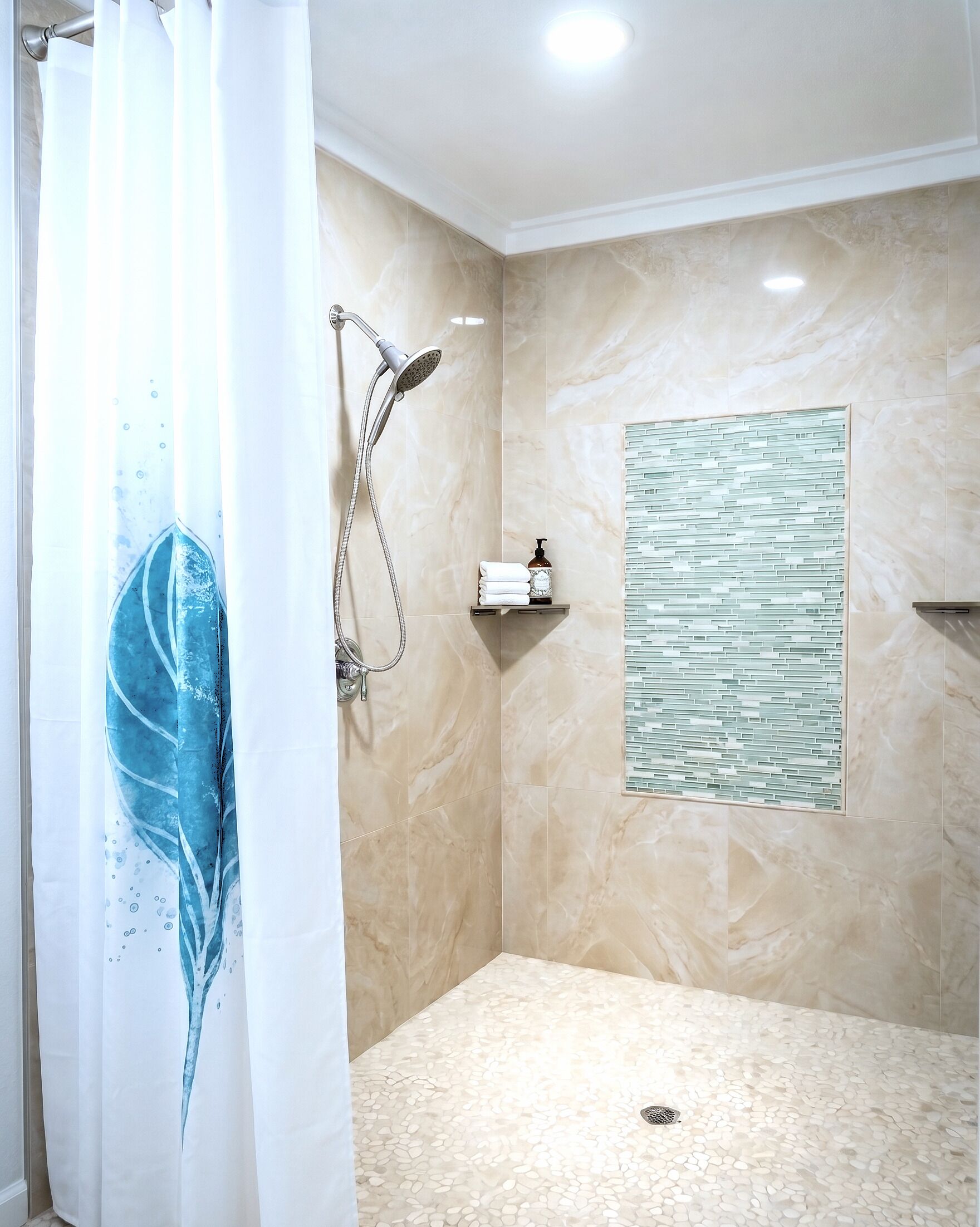 A shower with a handheld showerhead, a wall-mounted towel rack, and a decorative panel.