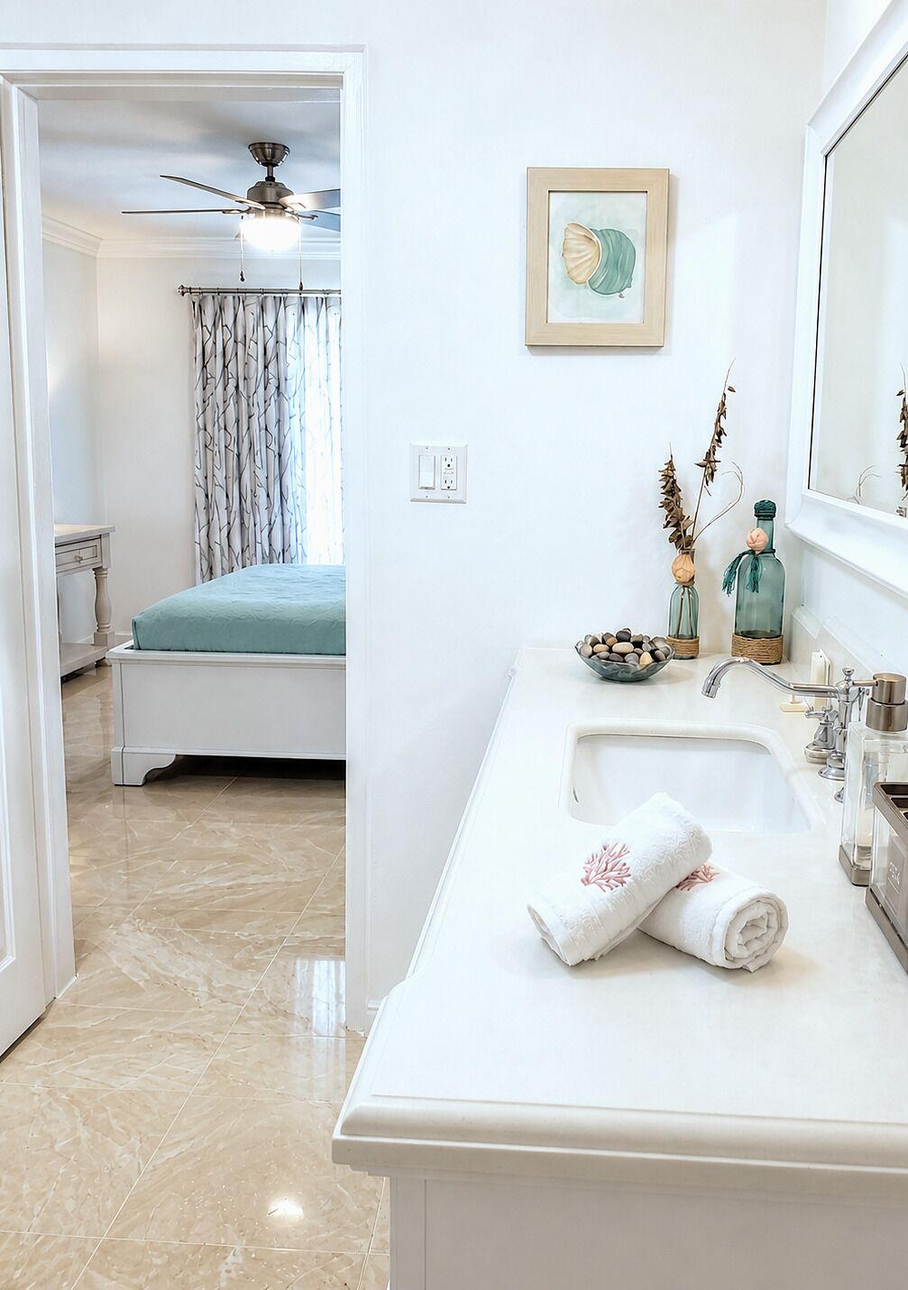 Un baño con lavamanos, espejo y toallero.